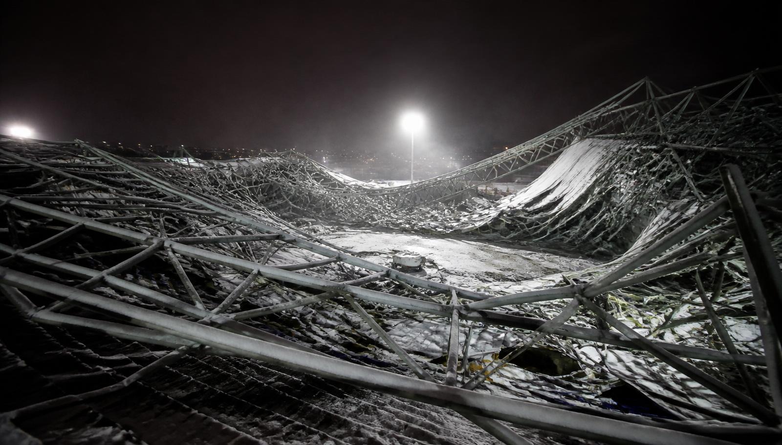 Collapsed steel space-frame roof under snow load at night